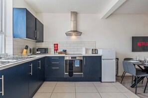 Eine moderne Küche mit dunklen Schränken, einer Edelstahl-Dunstabzugshaube, einer Mikrowelle, einem Toaster und einem Kühlschrank.