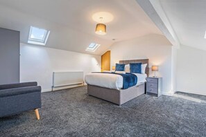 A modern bedroom with a large bed, a desk, a chair, a radiator, and a skylight. - 2 Bed Duplex | Jewellery Quarter | Sleeps 4 (West Midlands)