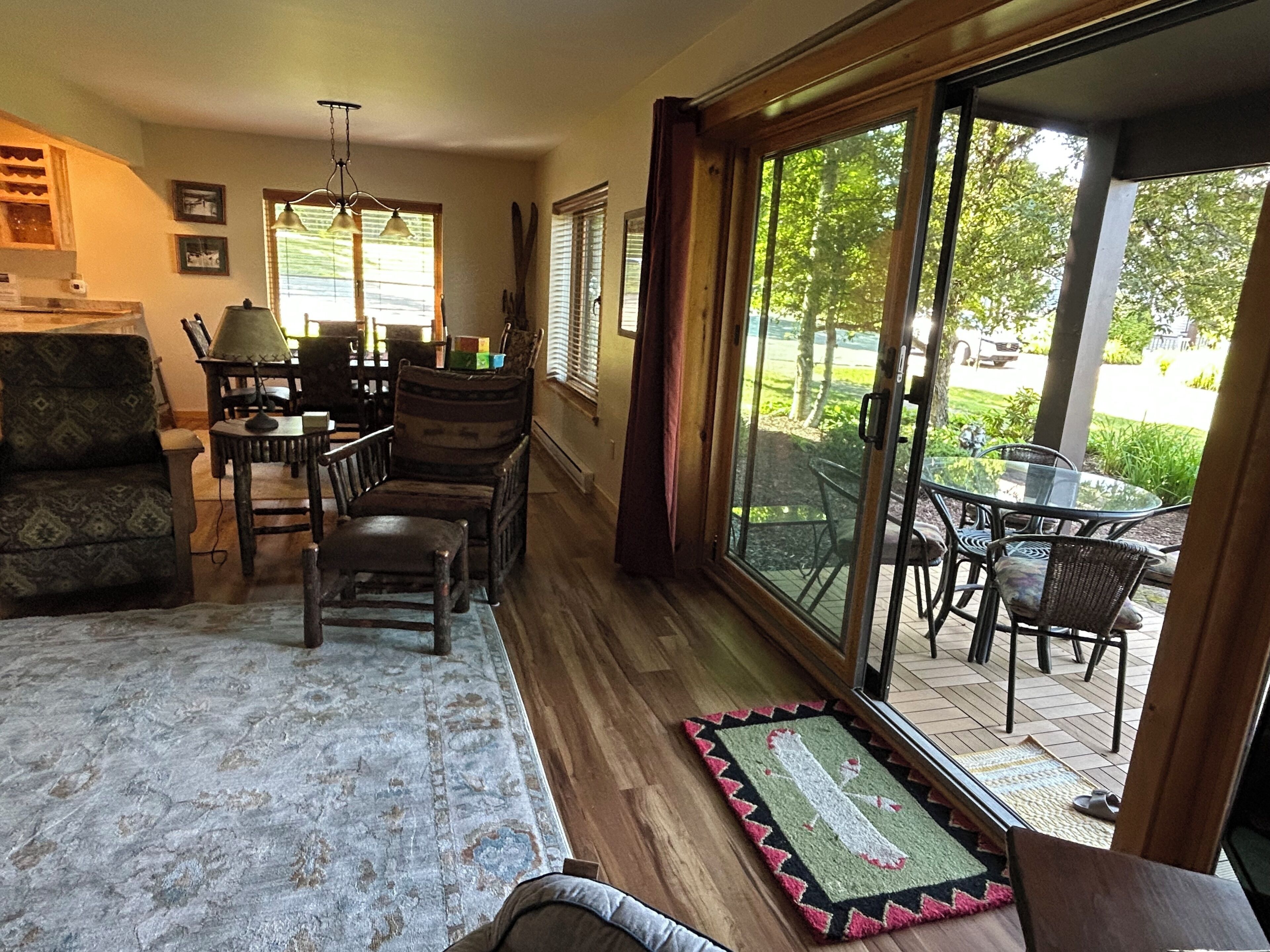A room with a dining area, a sofa, and a view through large glass doors to an outdoor patio.