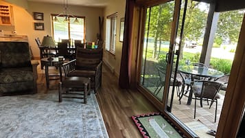 A room with a dining area, a sofa, and a view through large glass doors to an outdoor patio.