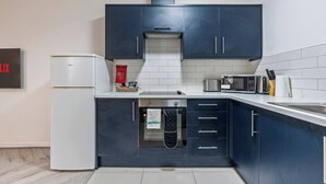 Une cuisine moderne avec des meubles de couleur bleu foncé, un réfrigérateur blanc, un four à micro-ondes et un grille-pain.