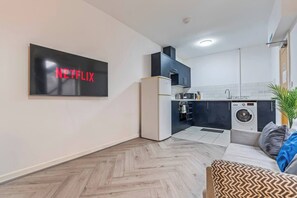 Une cuisine moderne équipée d’un four à micro-ondes, d’un four traditionnel et d’un lave-linge.