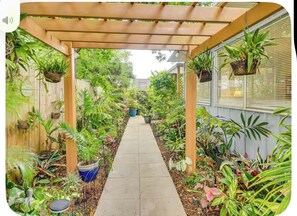 A covered garden pathway with potted plants on either side. - 'Palm Bungalow' Near Downtown St Augustine & Beaches! (St. Augustine)