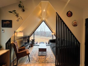 Un loft moderno con un tragaluz grande, un sofá, una mesa de centro y una escalera.
