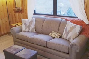 Un divano con cuscini decorati, un tavolino e una finestra con tende.