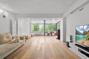 A spacious living room with a large flat-screen TV, a sofa, and a fireplace. - Luxurious villa with a pool, sauna, and garden, 15 minutes from Paris (Chatou)