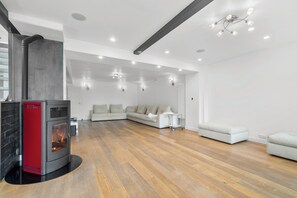 A modern living room with a wood-burning stove, a sofa set, and recessed ceiling lighting. - Luxurious villa with a pool, sauna, and garden, 15 minutes from Paris (Chatou)
