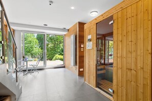 A modern interior with a glass door leading to a balcony, wooden walls, and a tiled floor. - Luxurious villa with a pool, sauna, and garden, 15 minutes from Paris (Chatou)