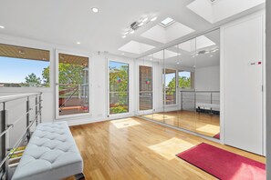 A modern interior with a wooden floor, a white sofa, and a glass door leading to an outdoor area. - Luxurious villa with a pool, sauna, and garden, 15 minutes from Paris (Chatou)