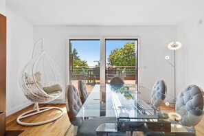A modern interior with a glass dining table, cushioned chairs, a hanging chair, and a view of the outdoors. - Luxurious villa with a pool, sauna, and garden, 15 minutes from Paris (Chatou)