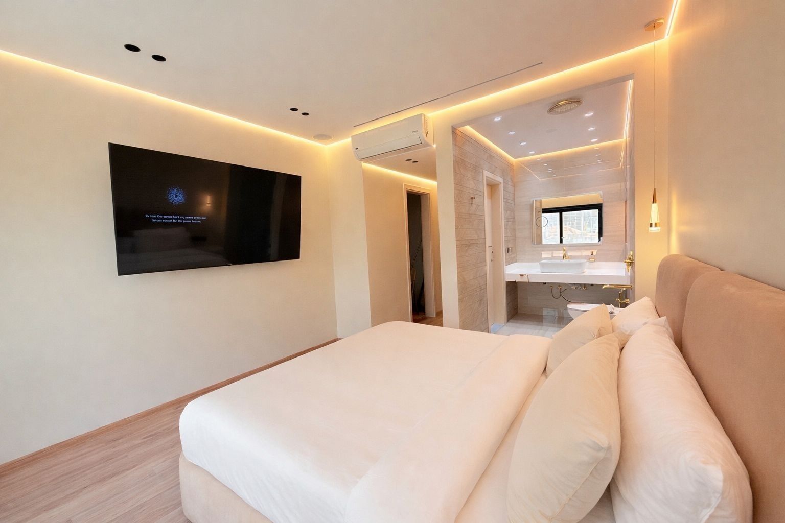Een moderne hotelkamer met een groot bed, een flatscreen televisie aan de muur en een badkamer met spiegel en wastafel.