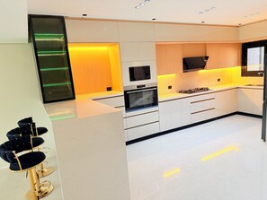 A modern kitchen with white cabinetry, a built-in oven, and a gas stove.