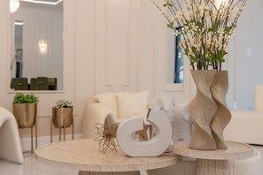 Un intérieur moderne avec une table ronde en bois, un vase contenant des fleurs blanches et un objet sculptural blanc.