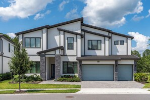 A modern two-story house with a garage, stone pillars, and a well-maintained lawn. - NEW Luxury 14BR Estate - Sleeps 36 - Theater/Games (Davenport)