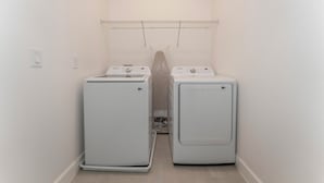 A laundry room with two white front-loading washing machines and a metal drying rack on the wall. - NEW Luxury 14BR Estate - Sleeps 36 - Theater/Games (Davenport)