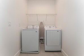 A laundry room with two white front-loading washing machines and a metal drying rack on the wall. - NEW Luxury 14BR Estate - Sleeps 36 - Theater/Games (Davenport)