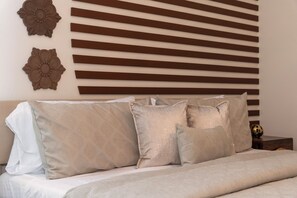 A bed with multiple pillows and a headboard against a wall with horizontal wooden slats and two wall-mounted flower decorations. - NEW Luxury 14BR Estate - Sleeps 36 - Theater/Games (Davenport)