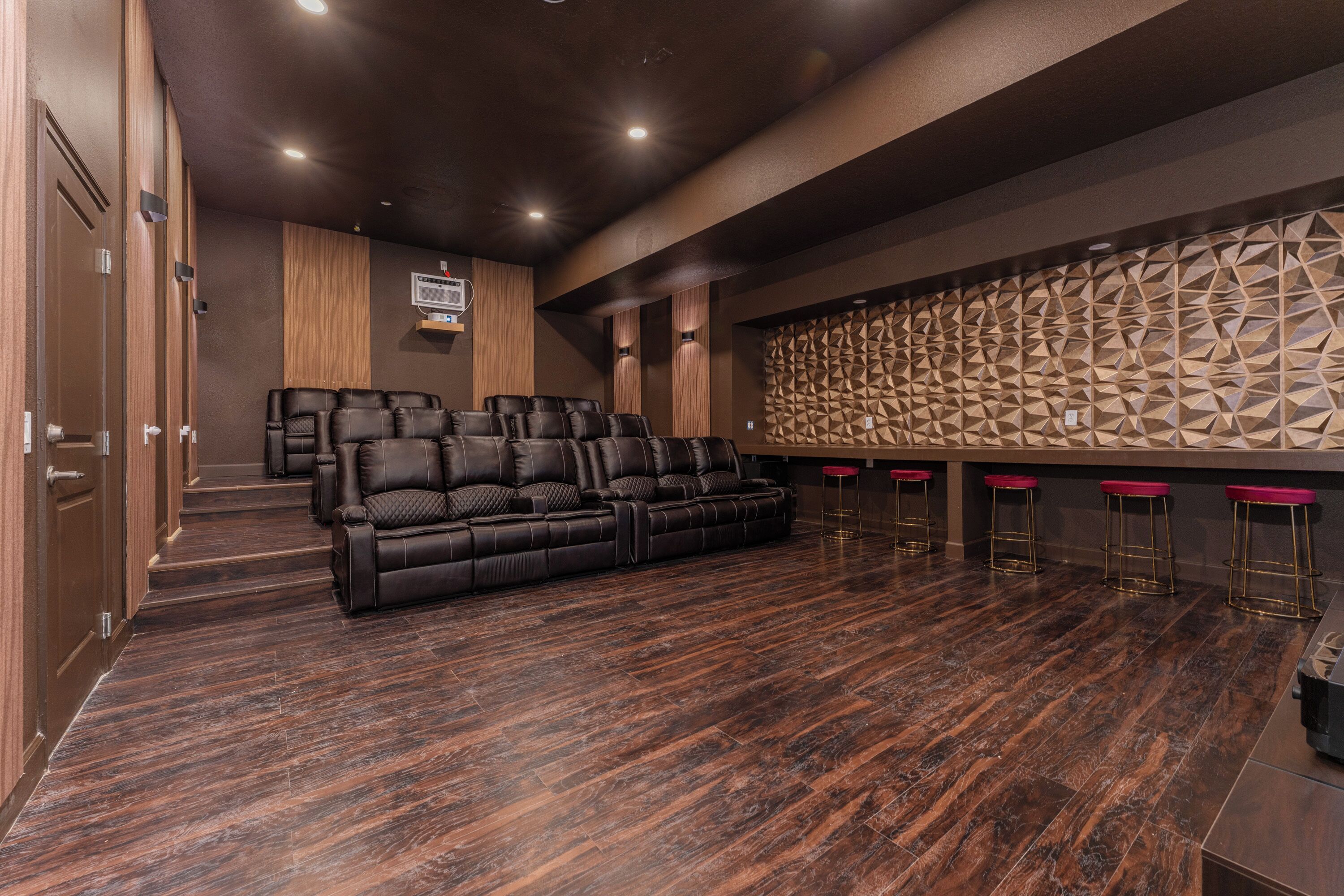 Un cine en casa moderno con un sofá seccional grande, un sistema de altavoces montado en la pared y un panel acústico estampado.