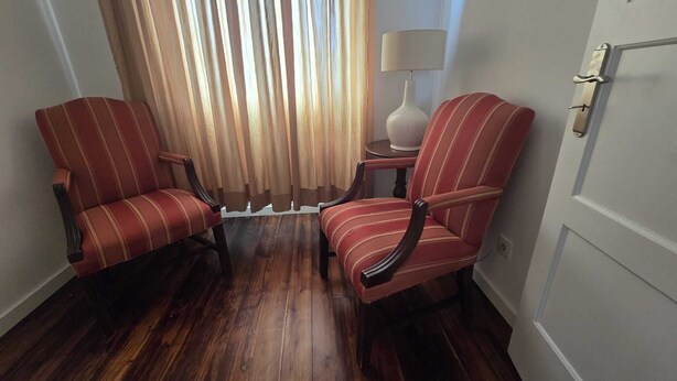 A room with two striped armchairs, a lamp, and a door. - Large and cozy apartment. Next to the António Borges Garden and Shopping Center (Ponta Delgada)