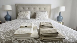 A neatly made bed with a patterned bedspread and two folded towels on the bed. - Cozy Premium I - Spacious, comfortable, welcoming (Ponta Delgada)