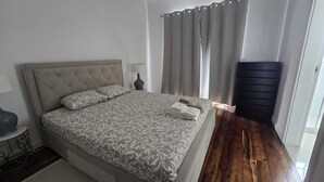 A neatly made bed with a patterned bedspread, a bedside lamp, and a stack of folded towels. - Large and cozy apartment. Next to the António Borges Garden and Shopping Center (Ponta Delgada)