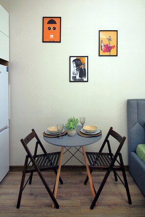 A dining area with a table set for two, two chairs, and three framed artworks on the wall. - Leon, Metro Raiymbek, 15 min to Arbat (Almaty)