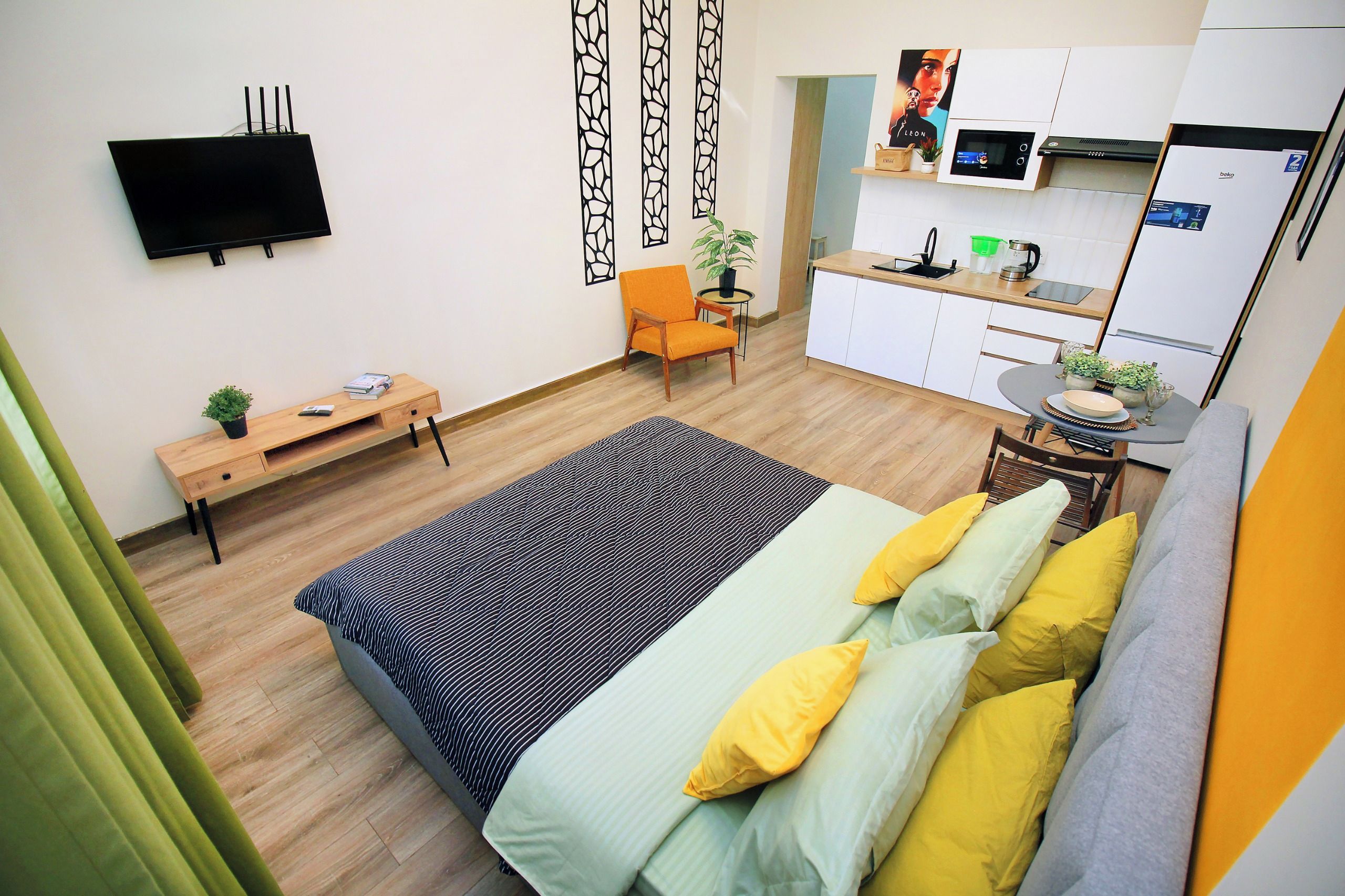 Habitació doble petita amb llit, escriptori, cadira i petita cuina.