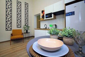 A modern kitchen with a microwave, a sink, and a countertop. There is a chair and a table with a bowl and a glass. - Leon, Metro Raiymbek, 15 min to Arbat (Almaty)