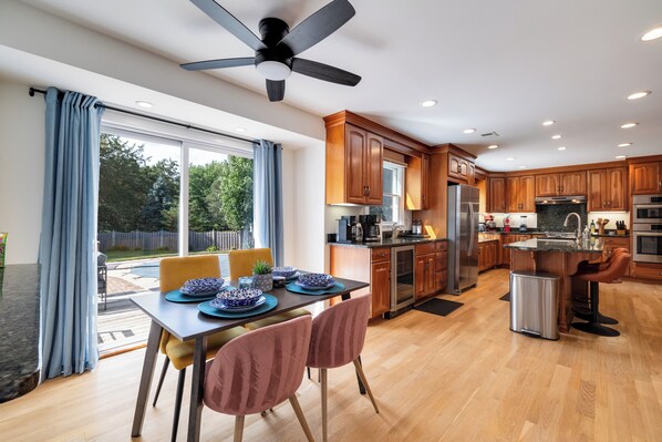 A modern kitchen with wooden cabinets, stainless steel appliances, and a dining area with a table set for four.