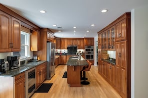 A spacious kitchen with wooden cabinets, a central island, and built-in appliances.