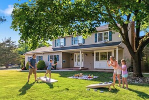 A residential house with a front porch, a lawn, and a tree.