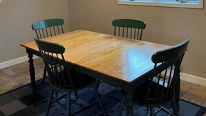 A dining room with a wooden table, four chairs, a ceiling fan, and a window with blinds. - Marvelous 4-bedroom house with AC in charming Port Austin (Port Austin)