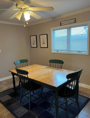 A dining room with a wooden table, four chairs, a ceiling fan, and a window with blinds. - Marvelous 4-bedroom house with AC in charming Port Austin (Port Austin)