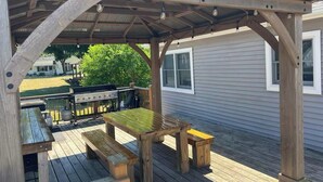 A wooden deck with a pergola, picnic table, and benches. - Marvelous 4-bedroom house with AC in charming Port Austin (Port Austin)
