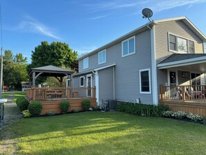 A two-story house with a covered porch, a satellite dish, and a well-maintained lawn. - Marvelous 4-bedroom house with AC in charming Port Austin (Port Austin)
