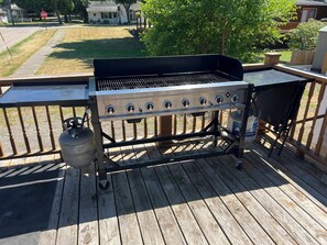 A barbecue grill on a wooden deck with a gas tank and a metal grill grate. - Marvelous 4-bedroom house with AC in charming Port Austin (Port Austin)