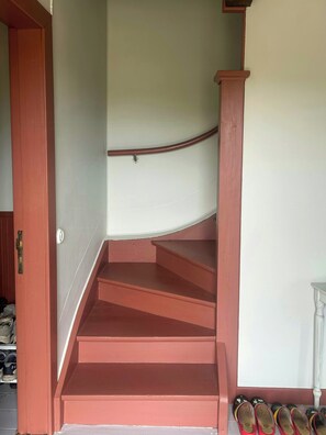 Eine Treppe mit Geländer und einer Tür zu einem Raum mit Schuhablage.