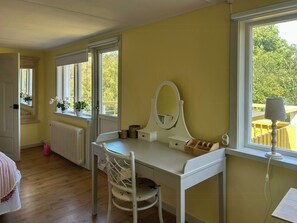 A room with a white vanity, a chair, a mirror, and a window with a view of greenery. - Farmhouse with view towards Kullaberg (BÅSTAD)