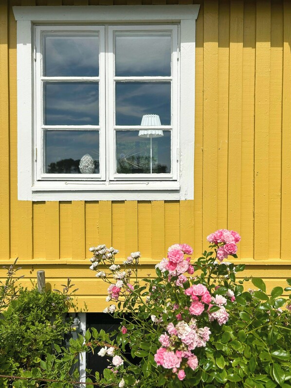 Un edificio amarillo con un marco blanco en la ventana y una lámpara blanca en su interior.