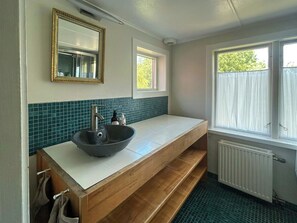 Ein Badezimmer mit einem Aufsatzwaschbecken, einem Spiegel, einem Fenster und einem Handtuchhalter.