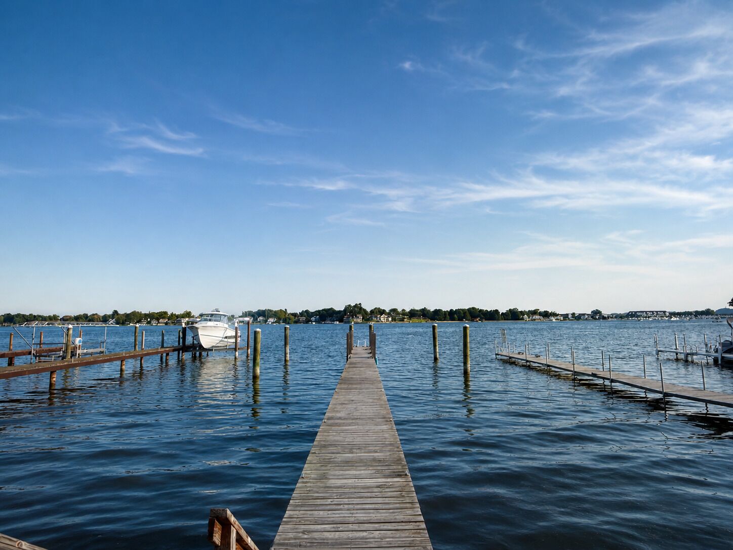 A wooden pier extending into calm water with a clear sky above.