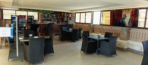 Zona de bar con asientos, una pantalla de televisión y una máquina expendedora.