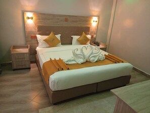 Ein Hotelzimmer mit einem großen Bett, einem Nachttisch und einem Beistelltisch.