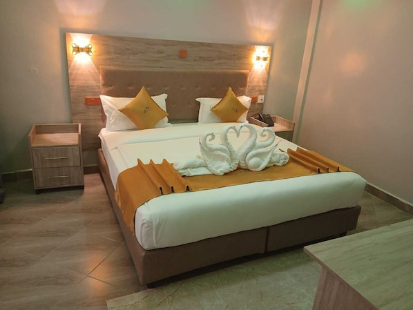 Una habitación de hotel con una cama grande, una mesita de noche y un velador.
