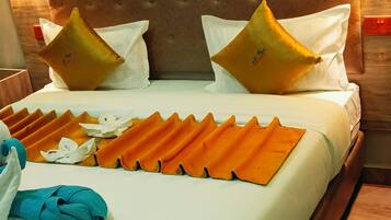 A hotel room with a bed, pillows, a blanket, and a folded towel.