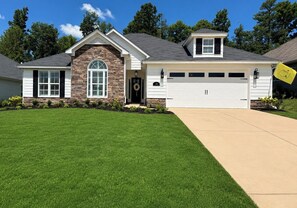 A two-story house with a stone facade, a garage, and a well-maintained lawn. - Exclusive Masters Retreat — Just Minutes from Augusta National (North Augusta)