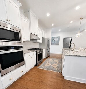 A modern kitchen with white cabinetry, stainless steel appliances, and a marble countertop. - Exclusive Masters Retreat — Just Minutes from Augusta National (North Augusta)