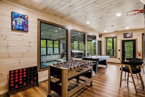 A room with a foosball table, a pool table, and a basketball hoop. - Luxe Indoor Pool | Sauna | Theater | Sleeps 16 (Sevierville)