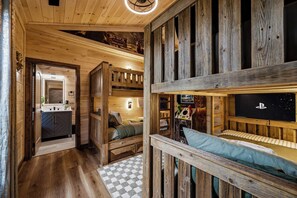 A cabin interior with a bunk bed, a small kitchenette, and a gaming console. - Luxe Indoor Pool | Sauna | Theater | Sleeps 16 (Sevierville)