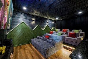 A cozy room with a wooden ceiling, a green accent wall, and a seating area with sofas and cushions. - Luxe Indoor Pool | Sauna | Theater | Sleeps 16 (Sevierville)